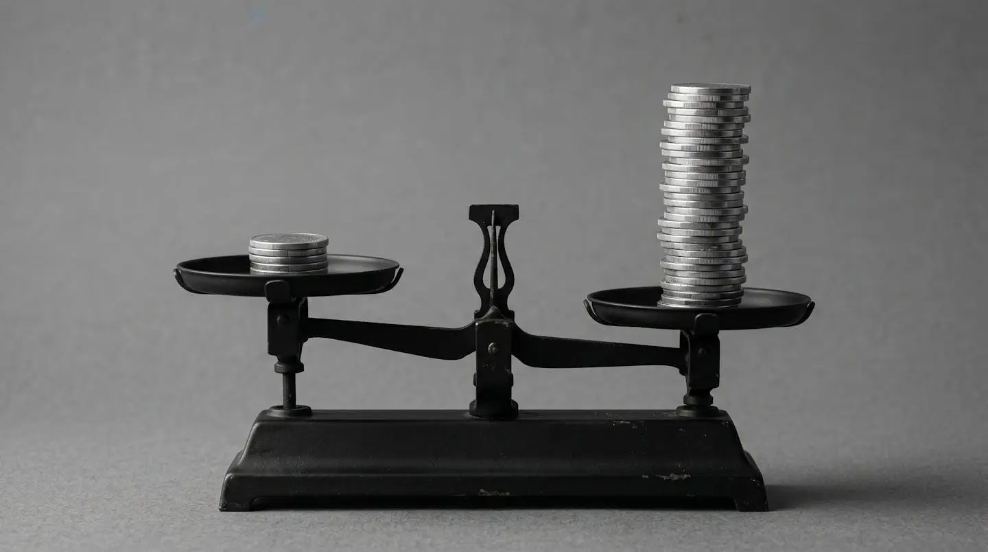 Balance ancienne déséquilibrée avec peu de pièces d'un côté et une grosse pile de l'autre, symbolisant l'arbitrage entre mensualités et coût total